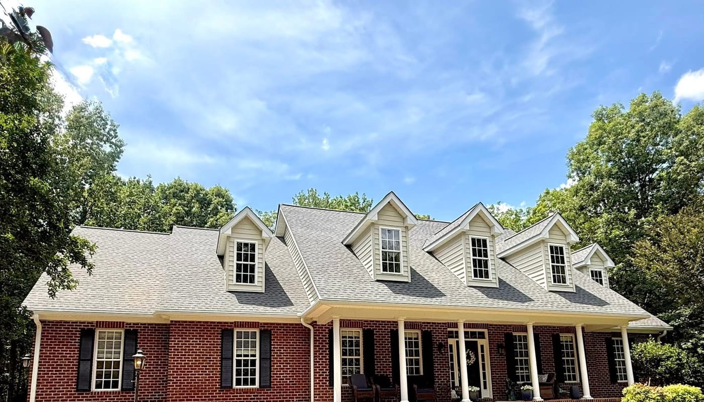 Completed shingle roof on a brick home with dormer windows in Virginia