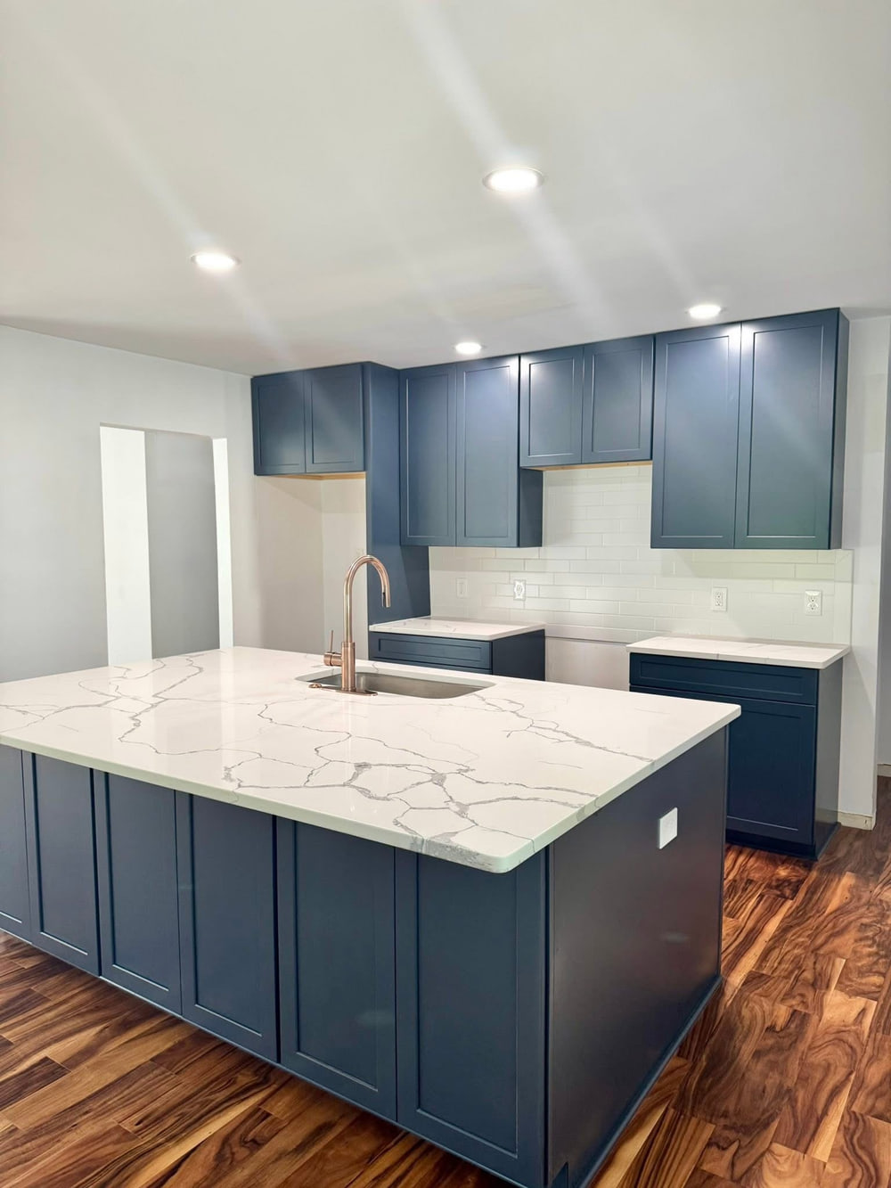 Navy shaker kitchen with quartz island and hardwood flooring